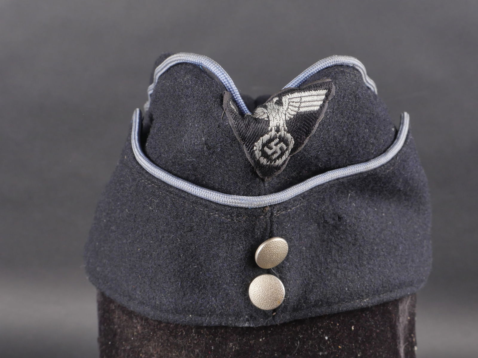 Calot NSDAP. NSDAP garrison cap.: Calot NSDAP en drap noir avec double boutons en metal grenele argente. Insigne tisse cousu main. Lisere bleu-gris cousu autour de la coiffure. Interieur double en tissu coton gris. Nombreux marquages
