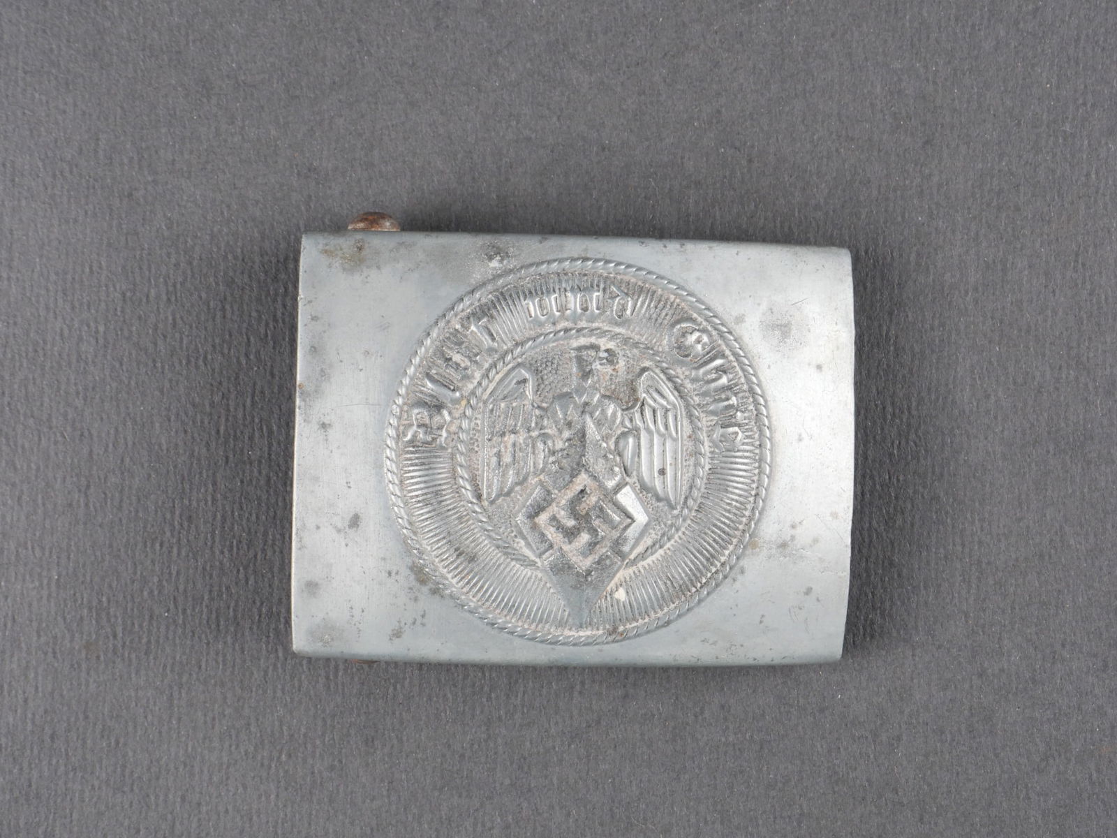Boucle de ceinturon Hitlerjugend. Hitlerjugend belt buckle: Boucle de ceinturon Hitlerjugend en zinc, version rare avec revers plein. Boucle a deux ardillons complete. Fabrication RZM M4/45. Usure et patine visibles. etat II+. Hitlerjugend belt buckle in zinc,