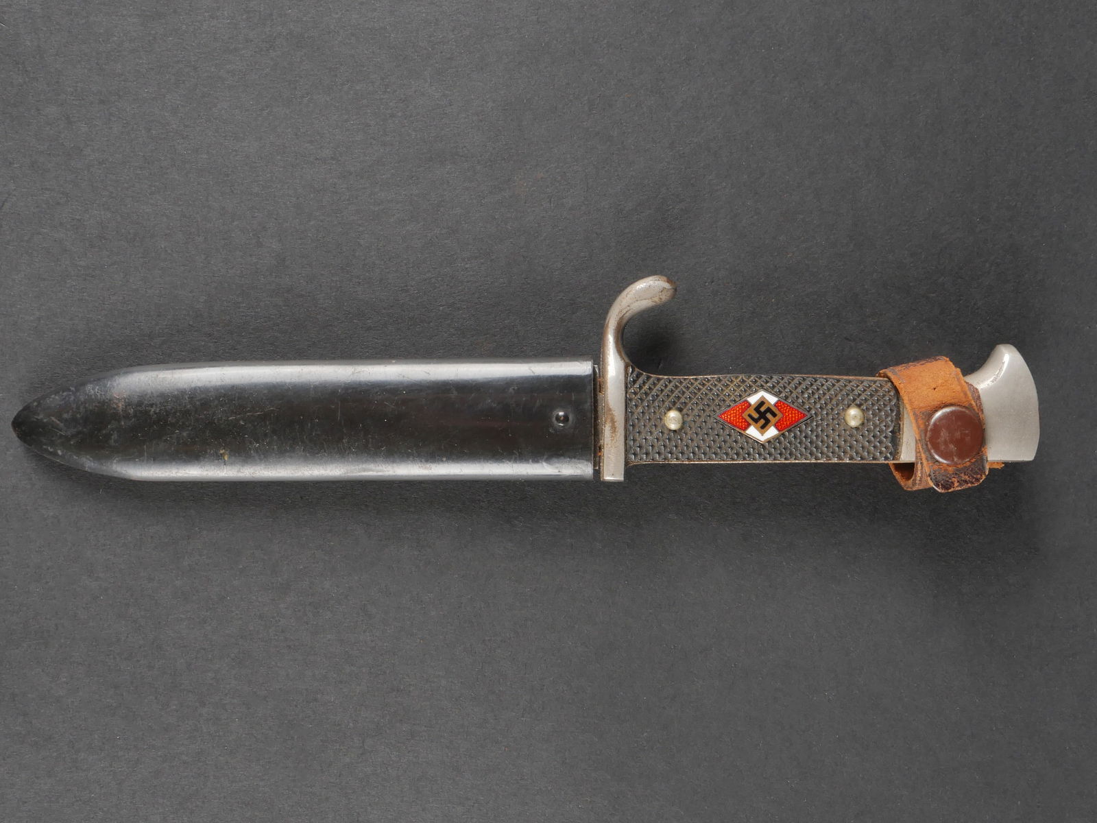 Couteau de marche Hitlerjugend. Hitlerjugend marching knife: Couteau de marche Hitlerjugend avec garniture en metal nickele et plaquettes en bakelite maintenues par rivets. Insigne Hitlerjugend en metal emaille remonte. Fourreau en metal peint a 80 %, gousset e