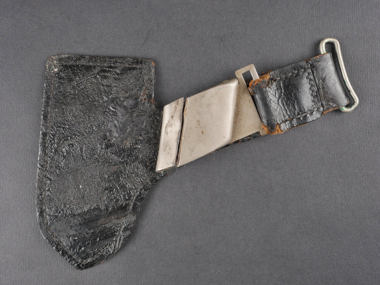 Beliere RAD. RAD belt hanger.: Beliere de dague du RAD en cuir noir bouilli. Mousqueton en metal bossele, anneau metallique tordu. Revers double de feutrine kaki, doublure partiellement absente. Aucun marquage visible. Presente une