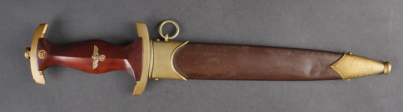 Dague de la SA. SA dagger.: Dague de la SA. Garnitures metalliques jaunies par le temps et la graisse. Poignee en bois verni. Bel insigne de la SA et aigle allemand fixes d’origine. Revers de la poignee marque en profondeur. G