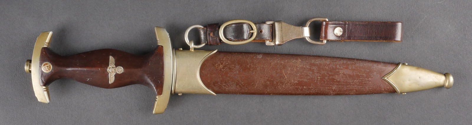 Dague de la SA. SA dagger.: Dague de la SA. Garnitures metalliques jaunies. Poignee en bois verni. Insigne de la SA et aigle allemand fixes d’origine. Revers de la poignee marque en profondeur. Garde portant le lettrage MNH. F