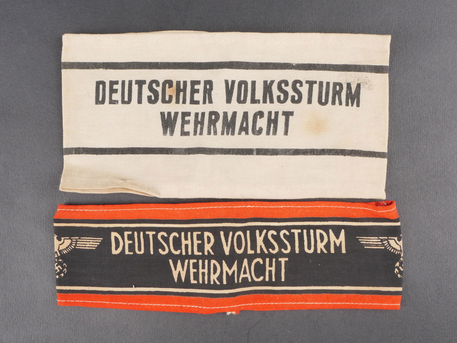 Brassards allemand. German armband.: Deux brassards allemands comprenant un brassard en tissu de coton blanc avec marquages imprimes Deutscher Volkssturm Wehrmacht et un second en tissu noir et rouge portant le meme marquage. Presentent