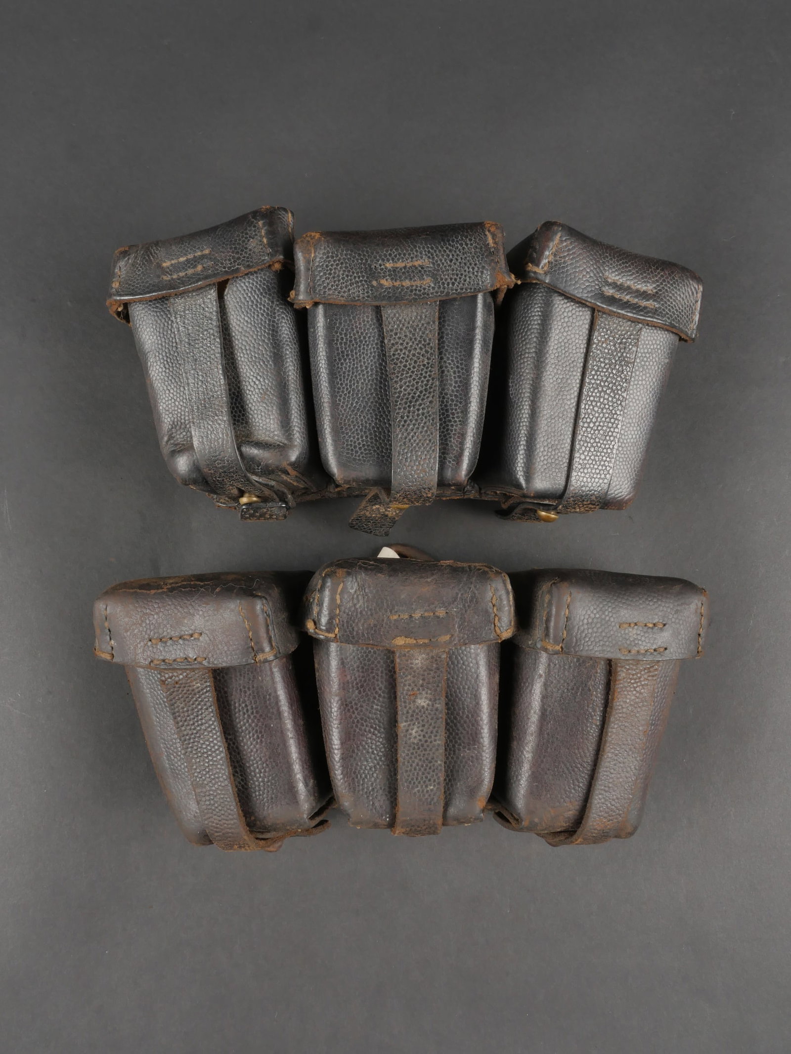 Lot de 2 cartouchieres allemandes modele 1909. Lot of Two German Ammunition Pouches Model 1909: Lot de 2 cartouchieres allemandes modele 1909. Toutes deux en cuir grenele, noirci de guerre, datees 1915, avec leurs sangles de fermeture, leurs passants, leur anneau de suspension. Lune a garnitures