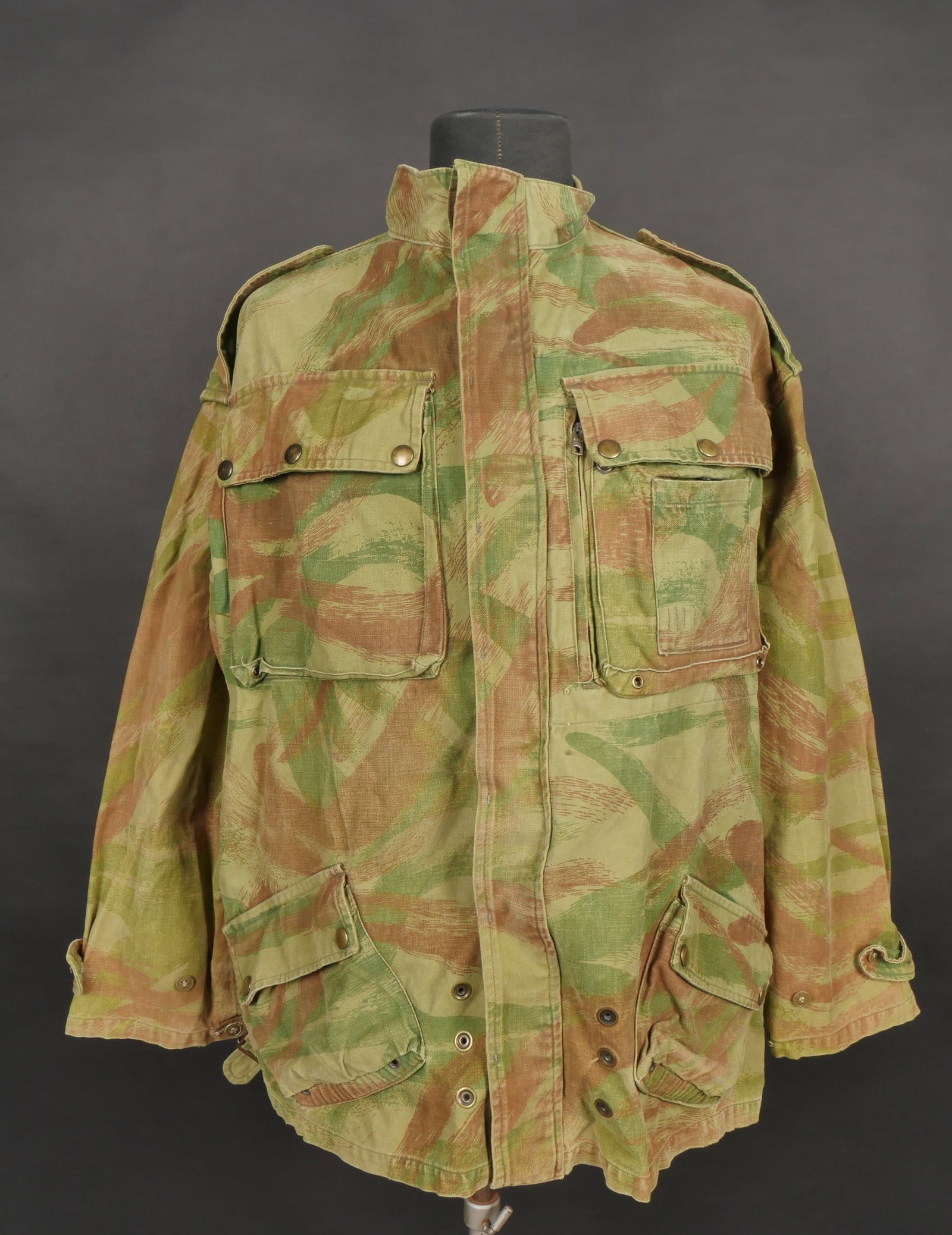 Veste TAP 4753 camouflee. TAP 4753 camouflage jacket: Veste TAP 4753. Veste confectionnee en coton camoufle et se fermant par huit boutons ainsi qu une fermeture eclaire Spidex, remplacee d epoque. Marquage fabricant au col Ariel, cachet d armee date 195