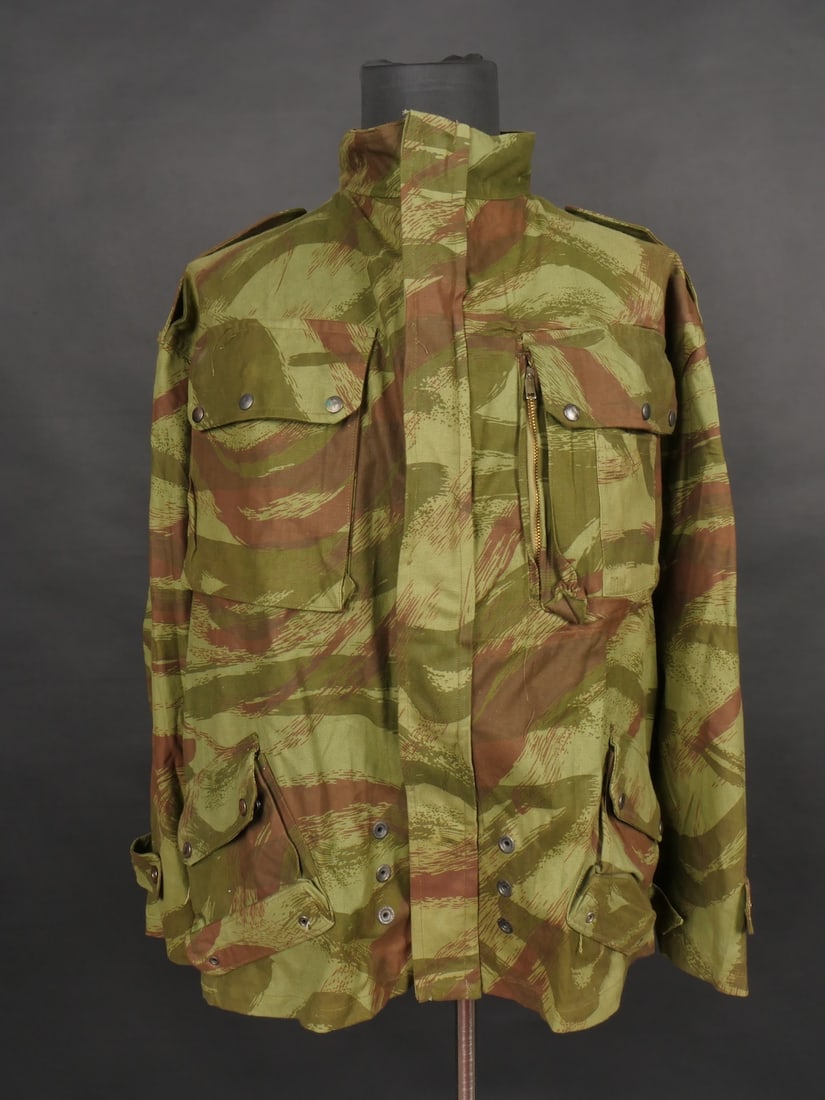 Veste TAP 4753 camouflee. TAP 4753 camouflage jacket: Veste TAP 4753. Veste confectionnee en coton camoufle et se fermant par huit boutons ainsi qu une fermeture eclaire Ailee. Marquage fabricant au col Chaumont Paris, taille 29. Queue de castor cousue d
