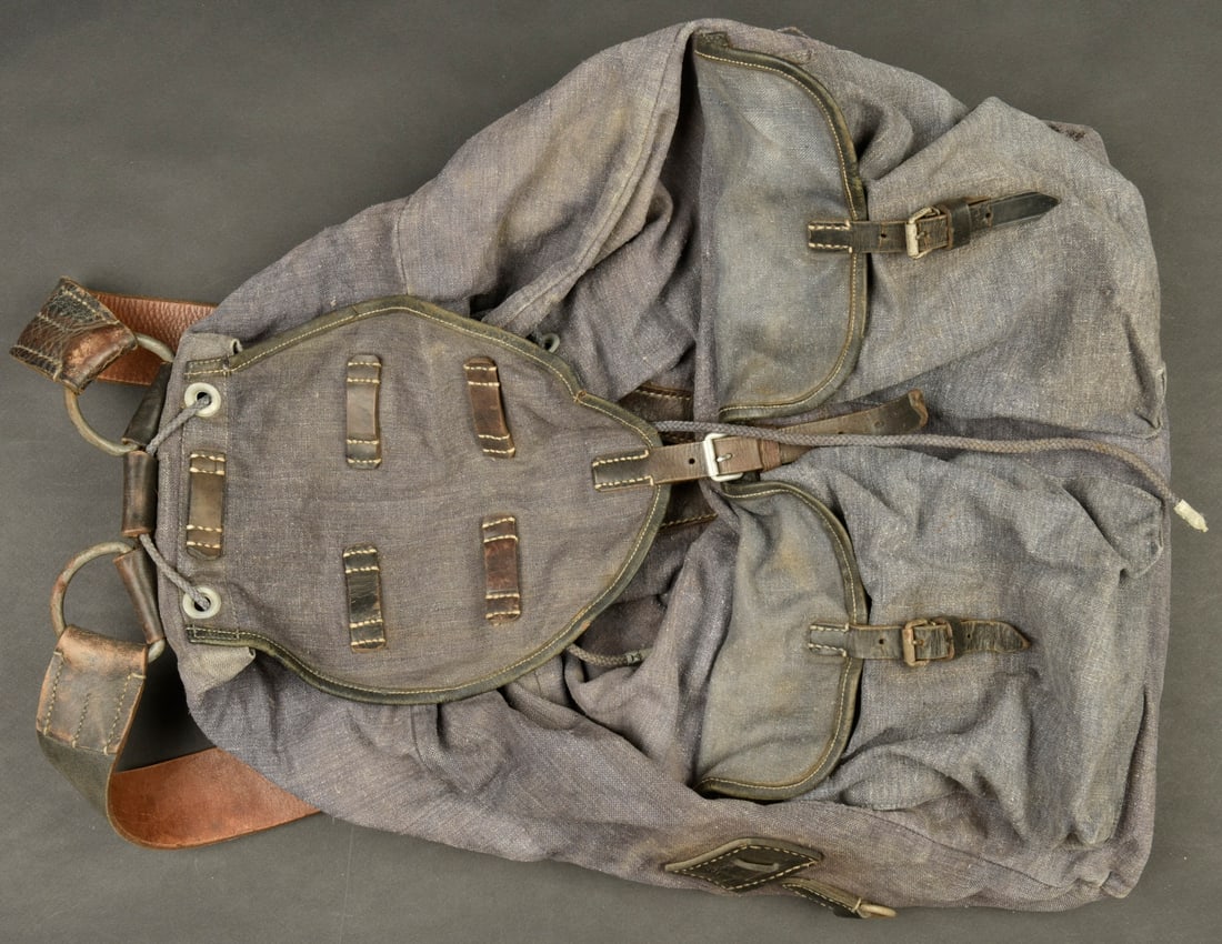 Sac a dos de la Luftwaffe. En epaisse toile gris/bleu. Et cuir noir. Le cordon de serrage est: Sac a dos de la Luftwaffe. En epaisse toile gris/bleu. Et cuir noir. Le cordon de serrage est present. Les bretelles en cuir noir sont completes. Fabrication M Thielsmann 1943. A noter une certaine us