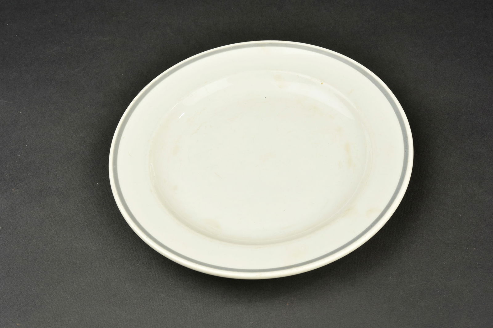 Assiette du DAF. En ceramique blanche et lisere gris. Diametre 21,5 cm. Bel insigne du DAF.: Assiette du DAF. En ceramique blanche et lisere gris. Diametre 21,5 cm. Bel insigne du DAF. Fabrication Bauscher Weiden. A noter une certaine usure et patine de la piece. Etat II+. Collection Lemarcha