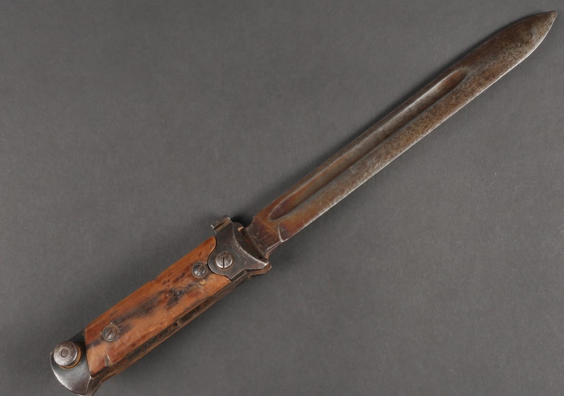 Baionnette PM Beretta. PM Beretta bayonet.: Baionnette pour pistolet mitrailleur Berreta. Modele pliante. Garnitures en metal et en tres bon etat. Plaquettes en bois, maintenues par deux rivets. Belle lame presentant une certaine usure. Les bou