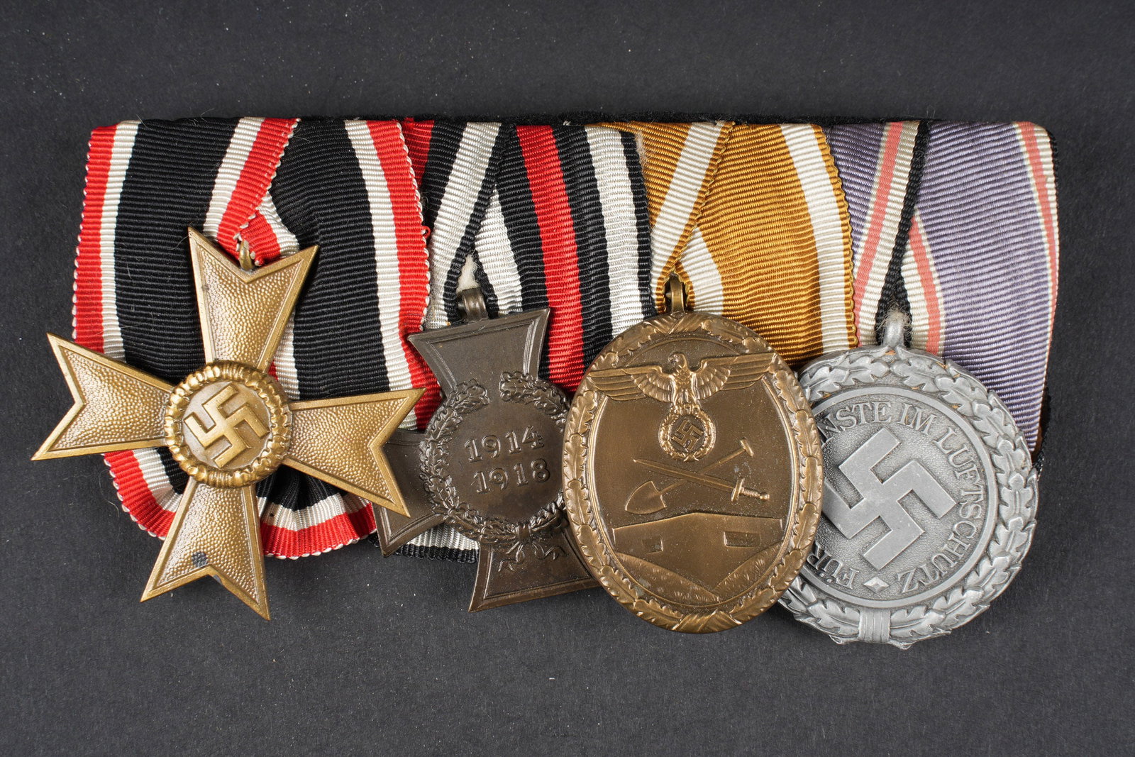 Barette de decorations. German insignia.: Barette de decoration. Modele avec decorations pendantes. Comprenant une KVK de seconde classe. Une medaille 1914-1918. Une medaille du Mur de lAtlantique et une medaille de service dans la Luftschutz