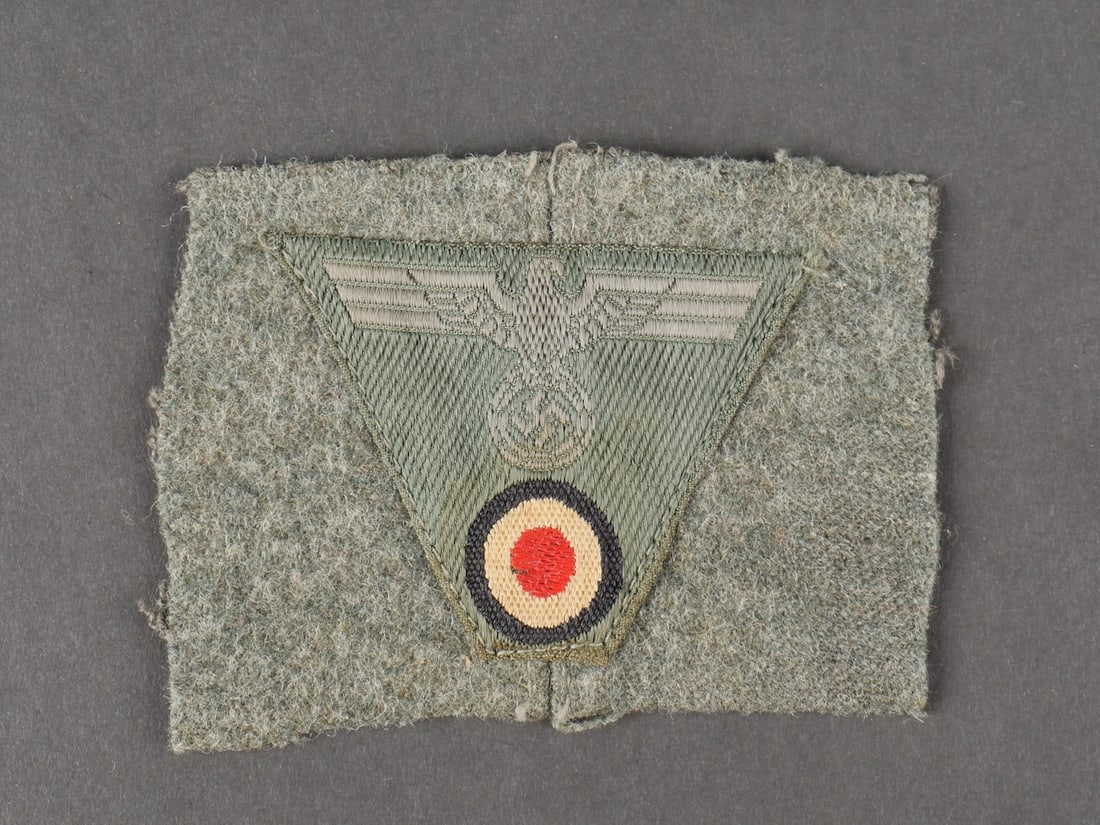 Insigne de coiffure M-43. German M-43 cap insignia.: Insigne de casquette M-43 de la Heer. Modele trapezoidal Bevo cousu machine sur un reste de drap Feldgrau. Aigle de manche SS. Celui-ci peut etre une prise de guerre dun GI US. A noter une certaine us