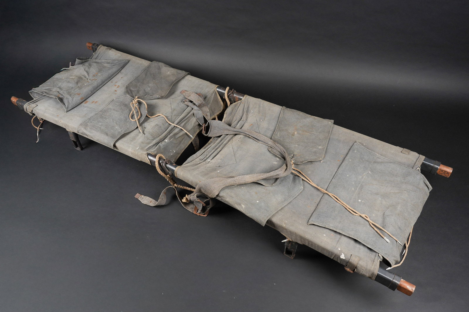 Brancard allemand. German stretcher: Brancard allemand. Armature en metal, couleur dorigine a 80%. Toile de couleur grisbleue, toutes les sangles sont presentes. Fabrication en deux parties. Les parties en bois disposent de marquages RAD