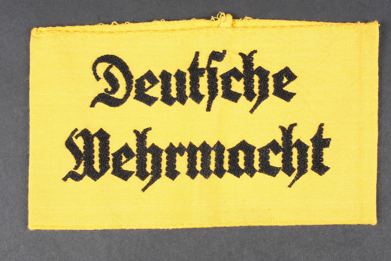 Brassard allemand. German armband.: Brassard Deutsche Wehrmacht. En tissu coton jaune. Marquages Deutsche Wehrmacht brode en fils noir. Les bordures sont partiellement effilochees. A noter une certaine usure et patine de la piece. Etat 
