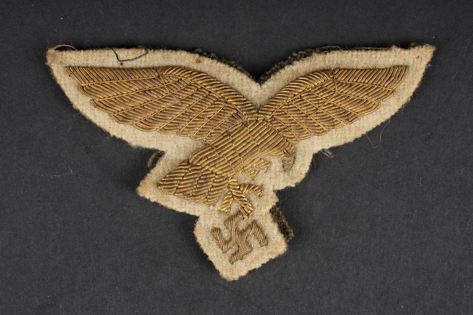 Aigle de general LW. General Luftwaffe eagle.: Aigle de poitrine de general Luftwaffe. En cannetille or sur fond en drap blanc, dos de la piece double d un tissu gris/bleu. Traces de colle au dos. Visiblement demonte d une vareuse. l authenticite