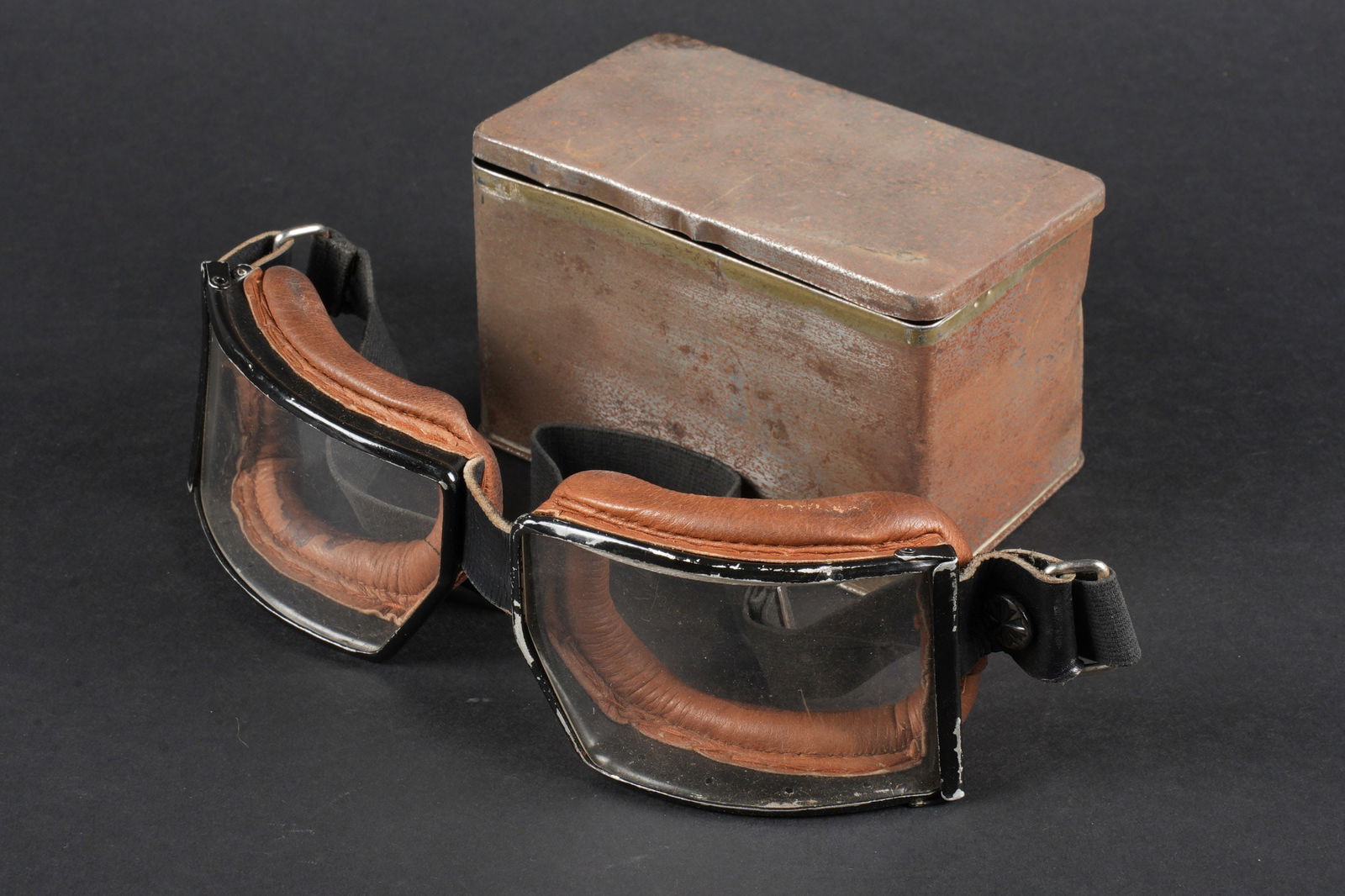 Lunettes allemande. German goggles.: Lunettes allemande. Armature en metal, couleur noire. Verres blanc. Doublure en cuir rembourre marron. Elastique souple. Boite en metal, quelques bosses visible. A noter une certaine usure et patine d