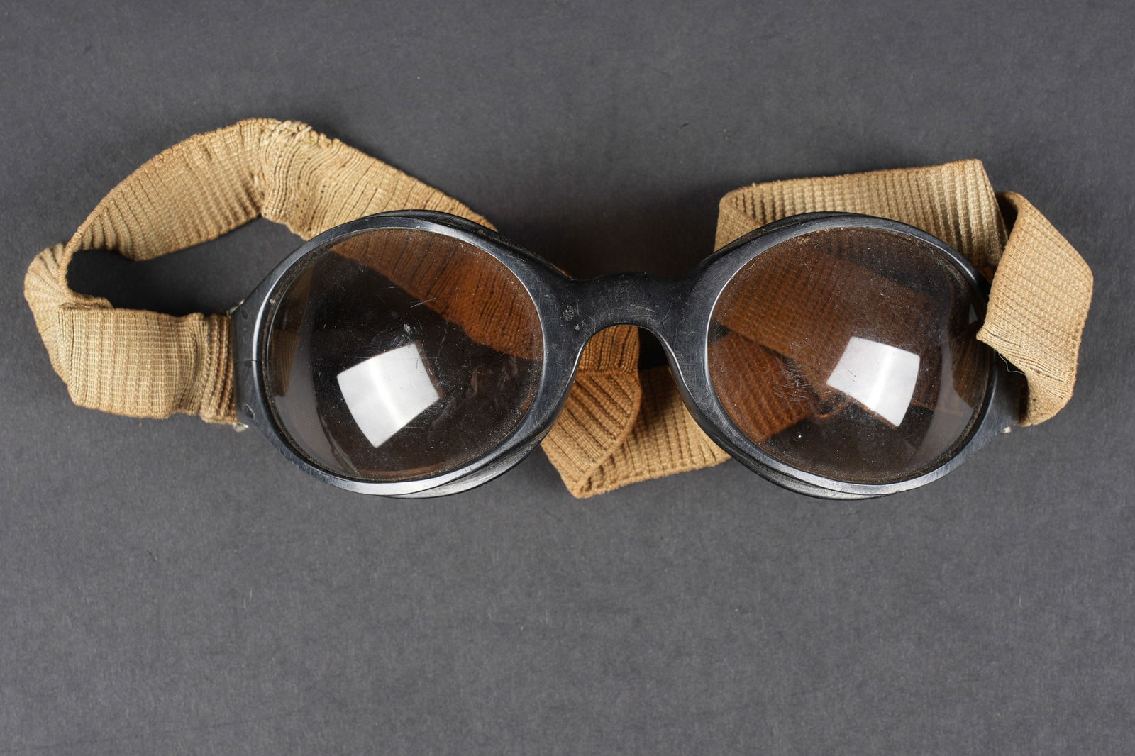 Lunettes de vol. Luftwaffe flying goggles.: Lunettes de vol allemande. Armature en bakelite noire. Verres fumes. Sans marquages visibles. Elastique de serrage partiellement distendu. Ensemble en parfait etat. A noter une legere usure et patine