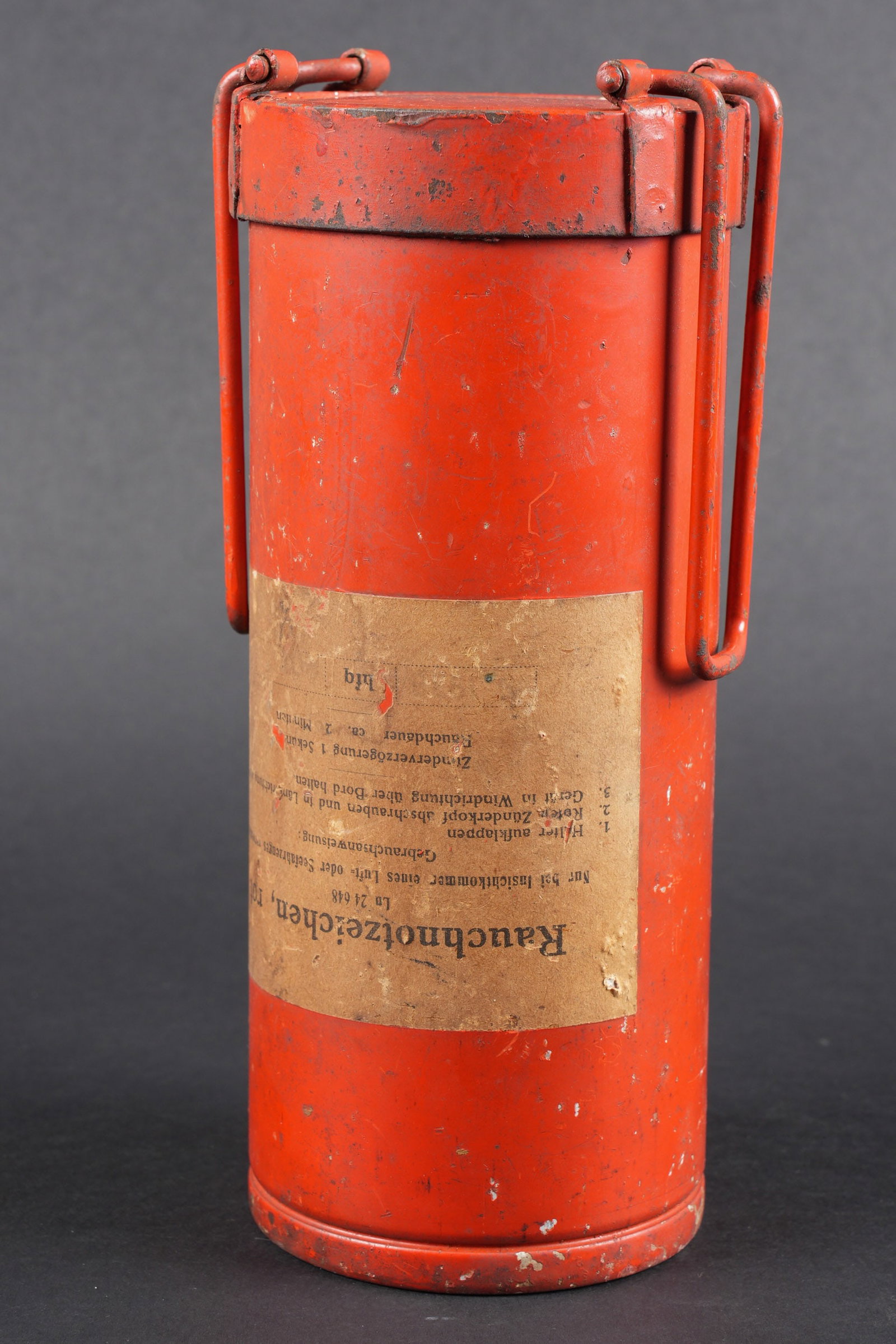 Fumigene de survie LW.: Fumigene de survie de la Luftwaffe. En metal, couleur rouge a 70%. Vide et inactif. Etiquette marquee Rauchnotzeichen rot, LN 24648. Fabrication HFQ, date illisibles. Utilisation que lorsqu'un avion o