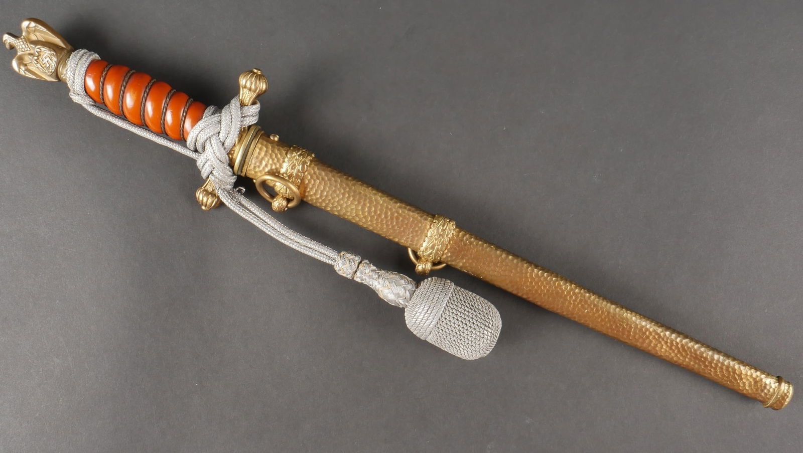 Dague Kriegsmarine. Kriegsmarine dagger.: Dague Kriegsmarine. Garnitures en metal dore. Poignee de couleur orange, filigrane en laiton. Dragonne couleur argent nouee de maniere reglementaire, presentant quelques marques d usures. Bouton pouss