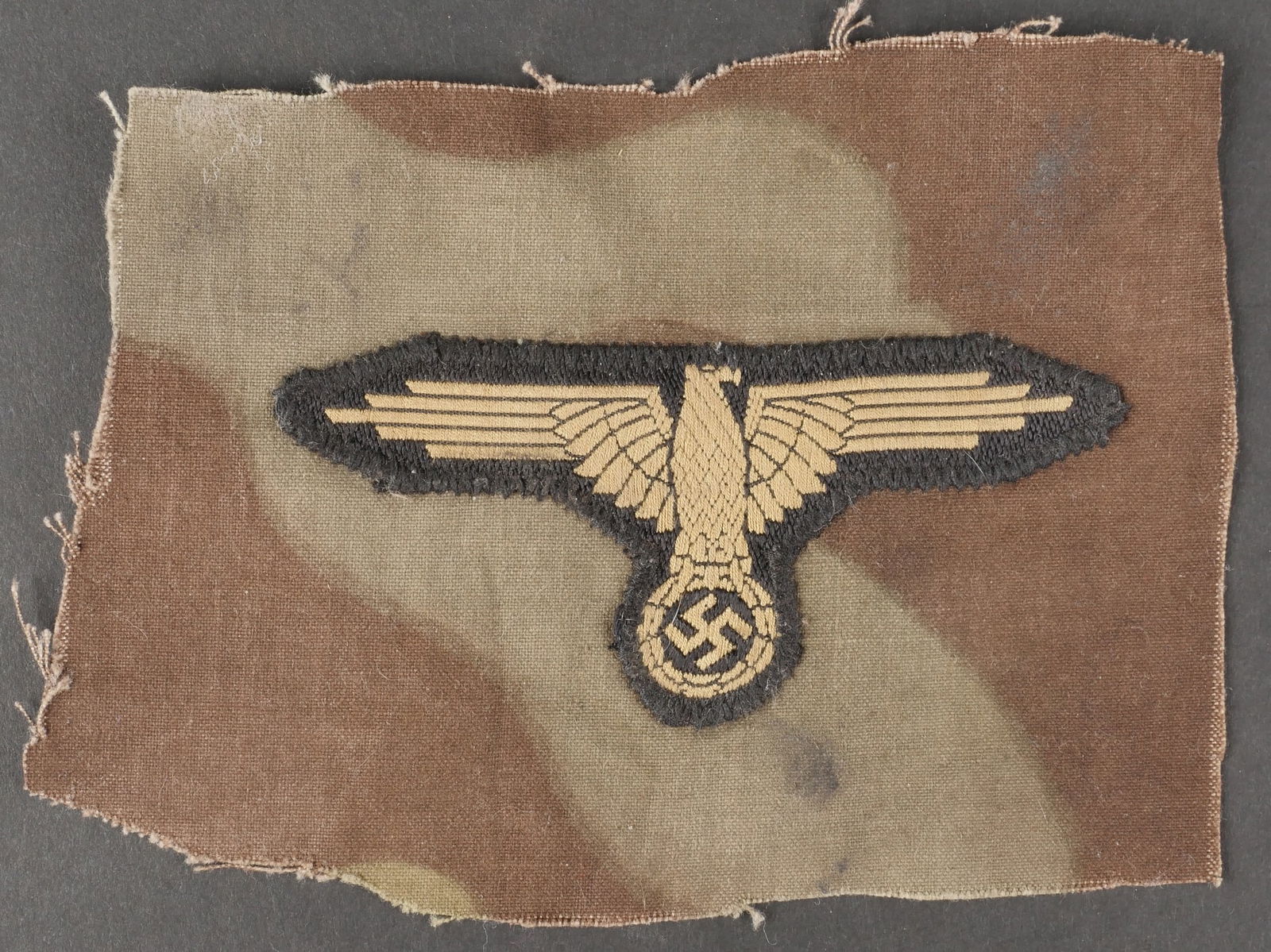 Aigle de manche SS. Waffen SS Sleeve eagle.: Aigle de manche SS. Modele tropical Bevo, cousu d origine sur un morceau de tissu camoufle italien. Provenant certainement d une vareuse italienne. Celui-ci peut etre une prise de guerre d un GI US. A