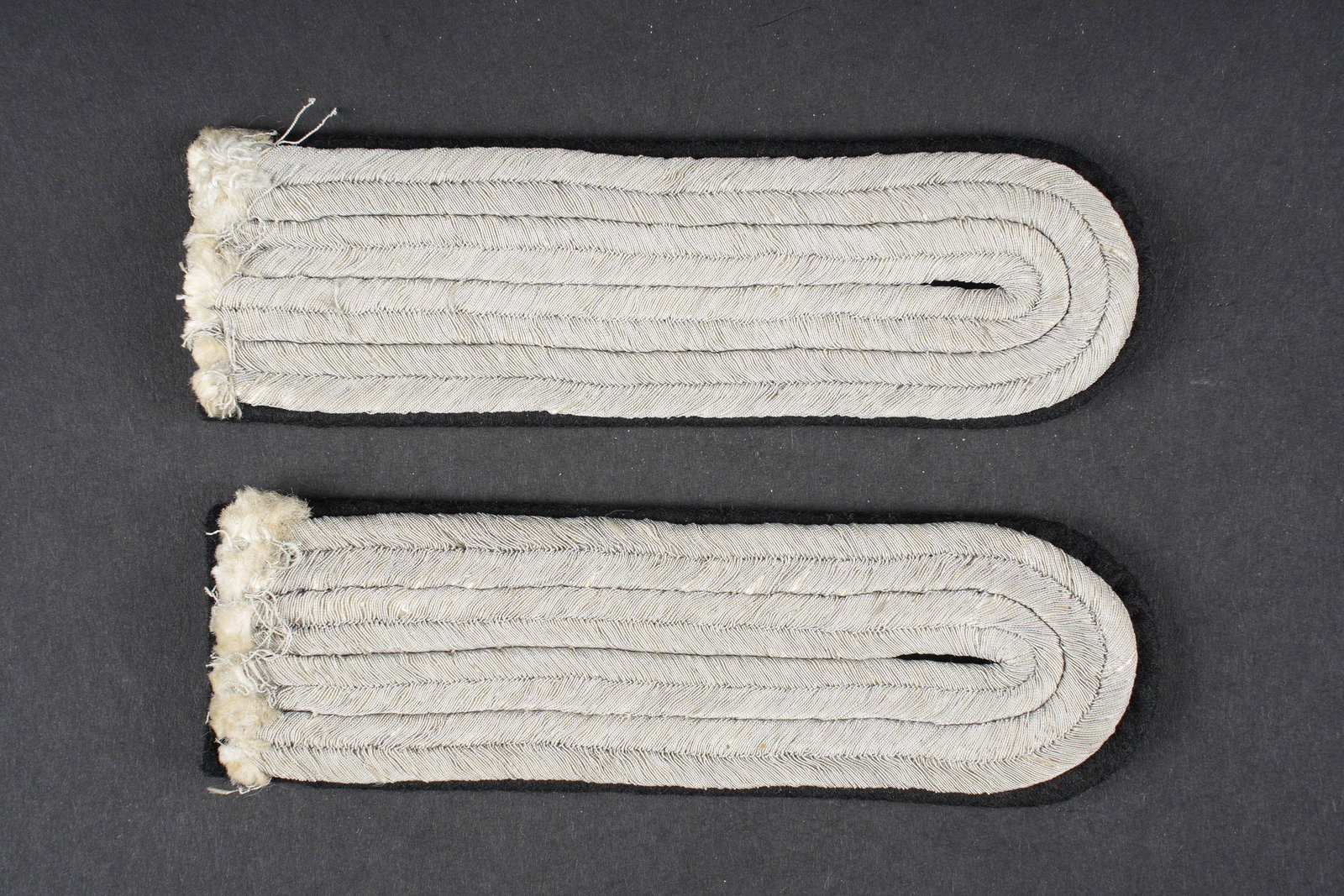Pattes d epaule officier SS. Waffen SS officer shoulder straps.: Pattes d epaules d officier SS. Paire homogene, grade d Untersturmfuhrer. Visiblement demontes d une vareuse. Plateau en drap noir. A noter une certaine usure et patine des pieces. Etat II+. SS Office