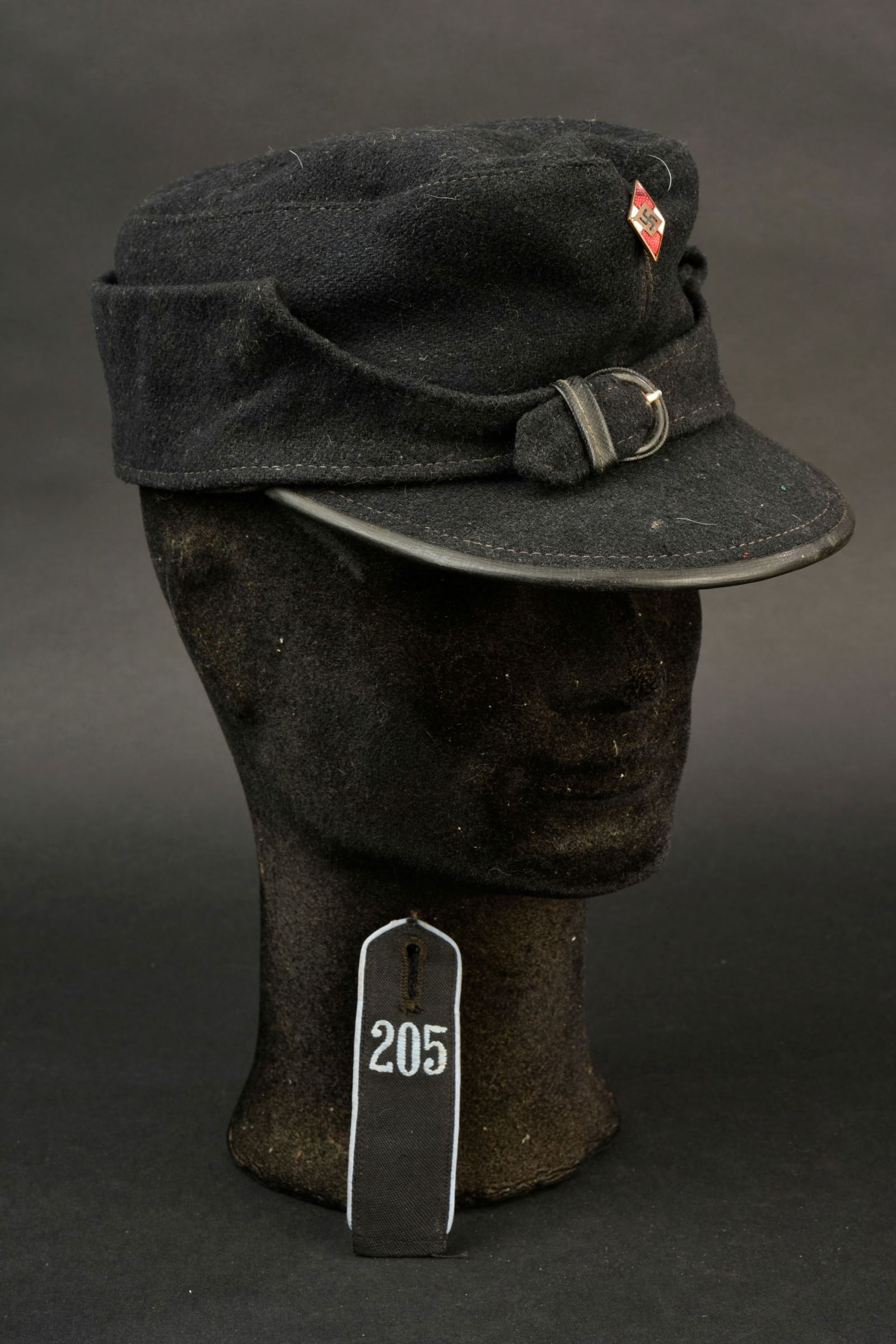 Casquette Hitlerjugend. Hitlerjugend cap.: Casquette Hitlerjugend. En drap bleu marine, modele civile. Rabat fermant par une boucle a ardillons. Doublure de la visiere en drap et bordure en cuir noir. Insigne de la Hitlerjugend en metal emaill