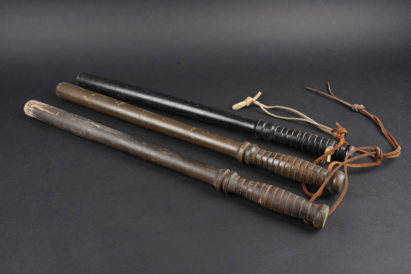Matraques Police. Law enforcement baton: Lot de 3 matraques de police. En bois, poignees striees, avec lacet de cuir. Longueur environ 55,5 cm. Probablement belges. Usure d usage. Lot of three police batons. Wooden construction with ribbed