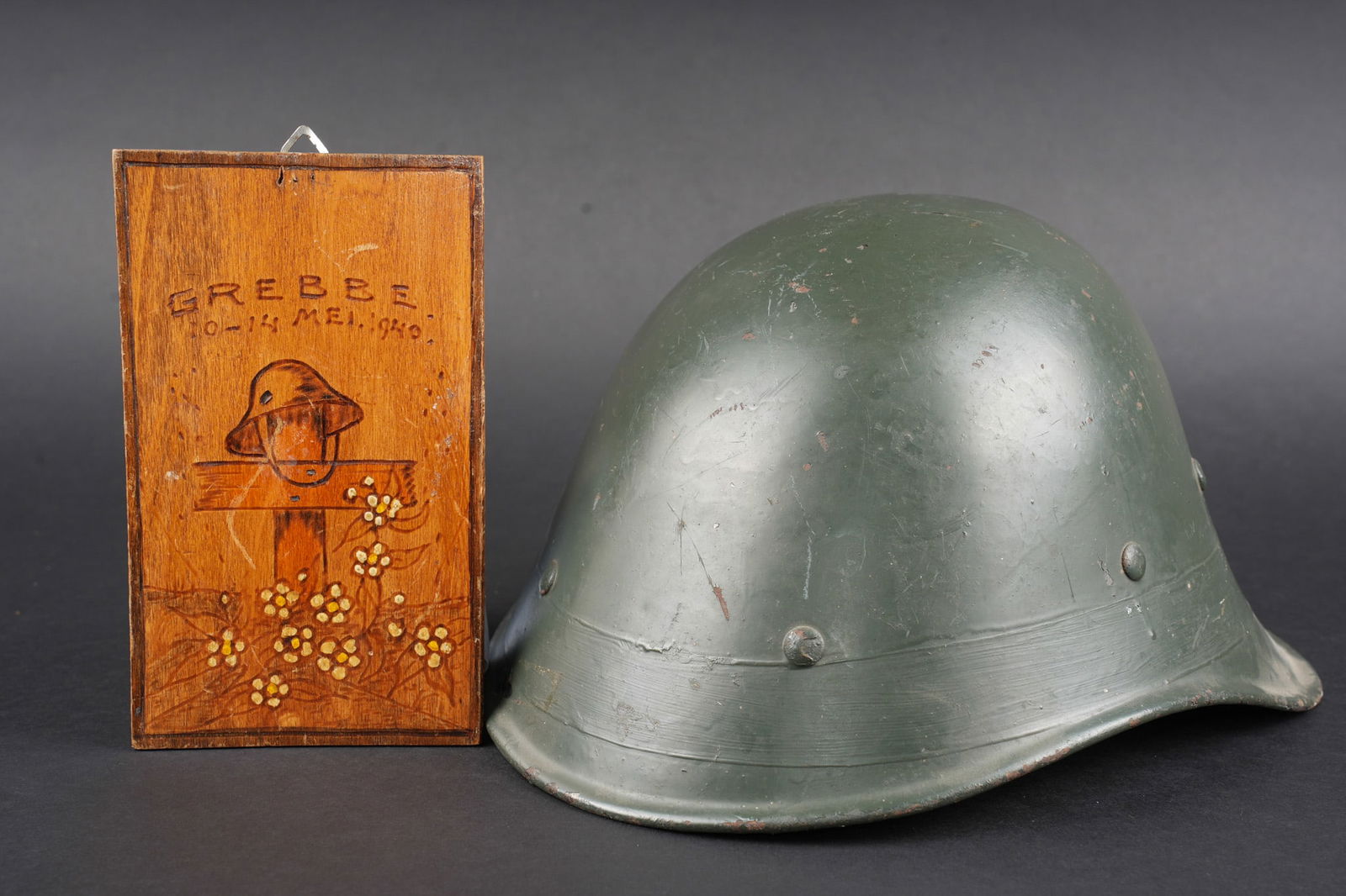 Pays-Bas casque 1934. Dutch Army helmet: Pays-Bas casque Modele 1934 protection civile. Avec sa coiffe en cuir marron, une demi jugulaire. Usure d usage. On y joint un petit panneau de bois commemorant les combats de frontiere a Grebbe en