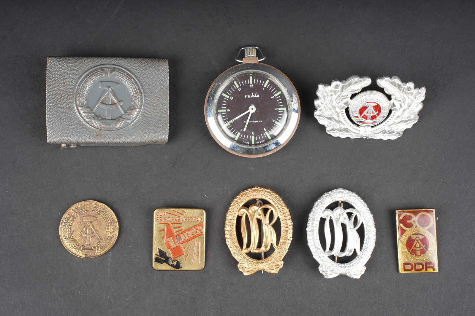 Lot DDR. DDR lot.: DDR lot insignes, boucle de ceinturon et montre. Montre Ruhla antimagnetique, fonctionnement non verifie, boucle DDR, insigne de coiffure, insignes de sport et divers, 8 pieces, usure d usage. East Ge