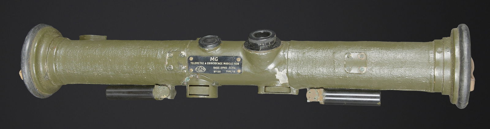 Telemetre francais SOM. French SOM Rangefinder: Telemetre francais SOM. Belle housse en forme de tube, toutes les sangles sont presentes. Quelques manques au niveau de la couleur. Couverture marquee SOM PARIS 51. Petit telemetre en metal, peinture