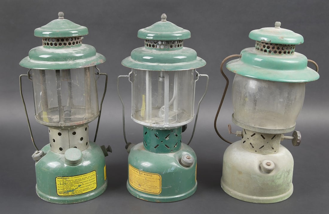 Lampes Colleman. Coleman lamps: Trois lampes colleman US. En metal emailles. Deux modeles differents. Les poignees de transport sont presentes. Peinture presente sur deux lampes. Une lampe n a plus de peinture a sa base. Les verres