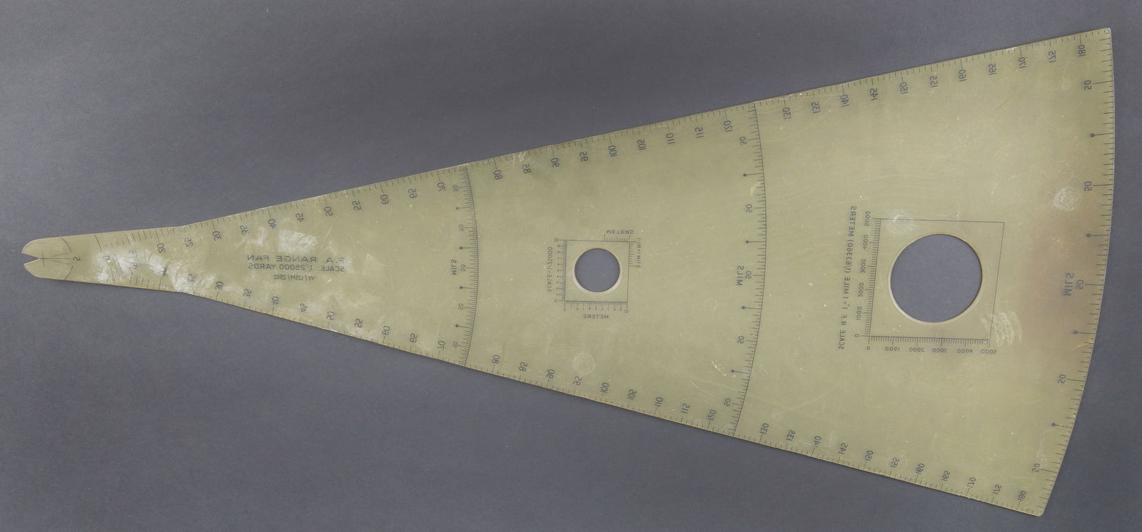 Regle de calcul US. US slide rule: Regle de calcul US. De forme triangulaire en bakelite transparent. Nombreuses fonctions de calcul. Marquages FA Range FAN Scale 1/25000 Yards VF/USM/2582. Dimensions 32 x 69,5 cm. A noter une