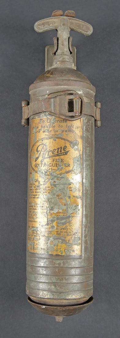 Extincteur de vehicule US. US vehicle fire extinguisher: Extincteur de vehicule US. Bouteille en metal, couleur marron a 70%. Quelques bosses visibles. Poignee complete. Fabrication Pyrene. Support de fixation au vehicule complet avec son attache