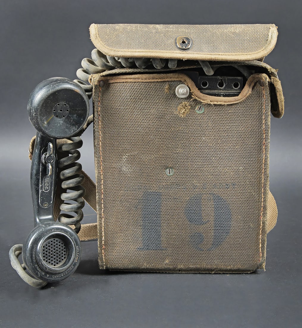 Telephone de campagne EE 8B. Field telephone EE-8B: Telephone de campagne EE 8B. Housse en toile impermeabilisee, presentant quelques deformations. Le bouton pression est fonctionnel. La sangle de transport est presente. Chiffre 19 peint en noir sur