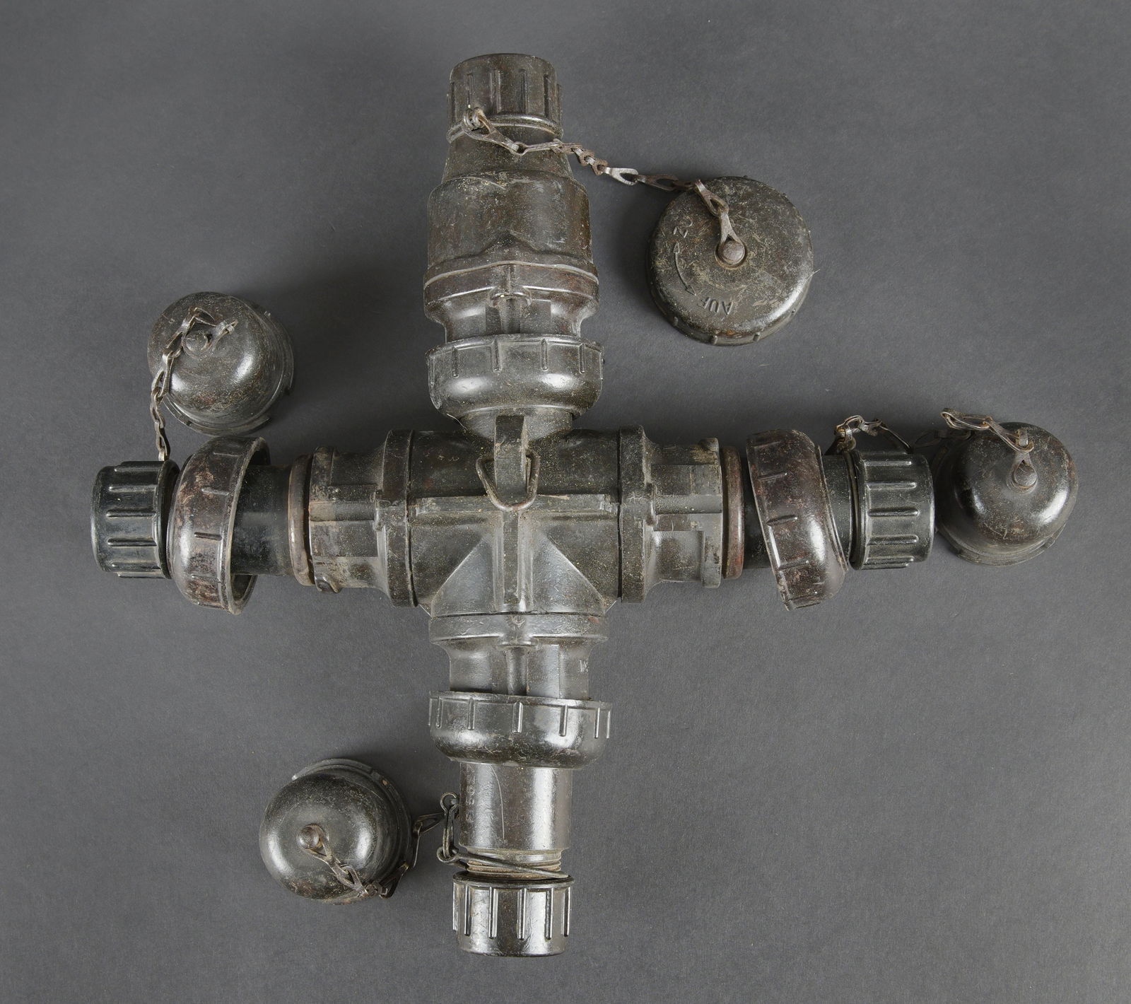 Boite de derivation electrique Flak. Flak electrical junction box: Boitier de derivation electrique de la Flak. En bakelite, sous forme de croix. Tous les bouchons sont presents, ainsi que les chainettes. Code FL partiellement illisible. A noter une certaine usure et