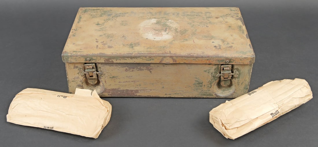 Verbandkasten. Verbandkasten: Verbandkasten. Caisse en metal. La poignee de transport est presente. Les crochets de fermeture sont fonctionnels. Peinture et marquages frotte et partiellement decapes. Rack interne present. Notice