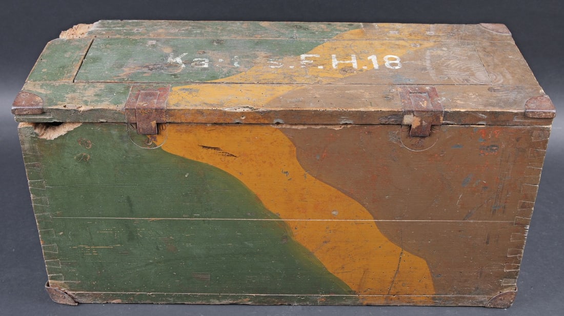 Caisse SFH18 camoufle. SFH 18 ammunition crate, camouflaged.: Caisse camoufle SFH18 camoufle. En bois. Peinture camoufle d usine a 70%. Les poignees de transport sont presentes. Couvercle fortement abime et partiellement desolidarise du reste de la caisse. Marqu