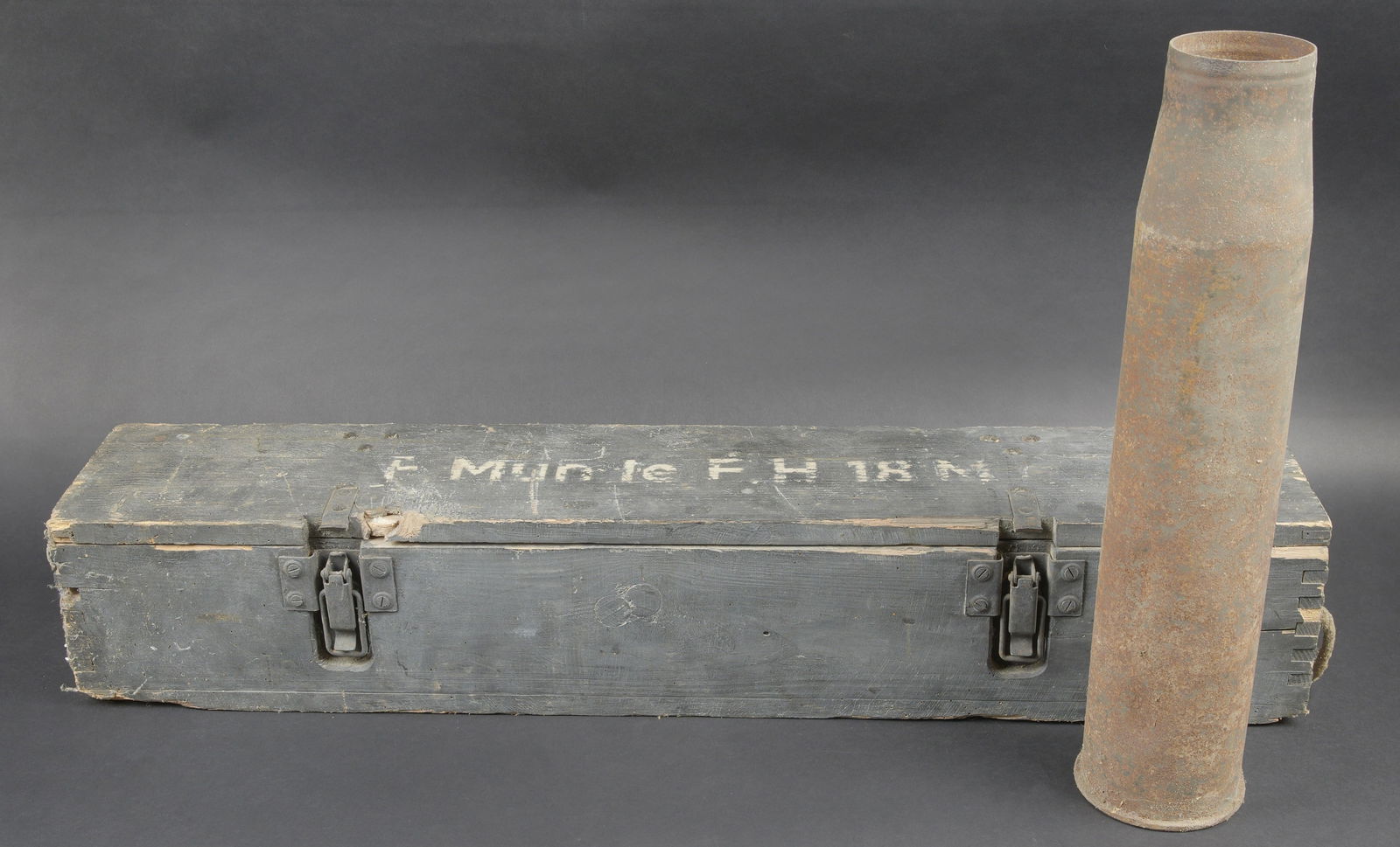 Caisse FH 18M. Ammunition crate for le.F.H.18M.: Caisse FH 18M. En bois, peinture a 70%. Quelques manques dans le bois. Les cordelettes de transport sont manquantes. Couvercle marque F Mun Le FH 18M. Les crochets de fermeture sont presents. Les cale