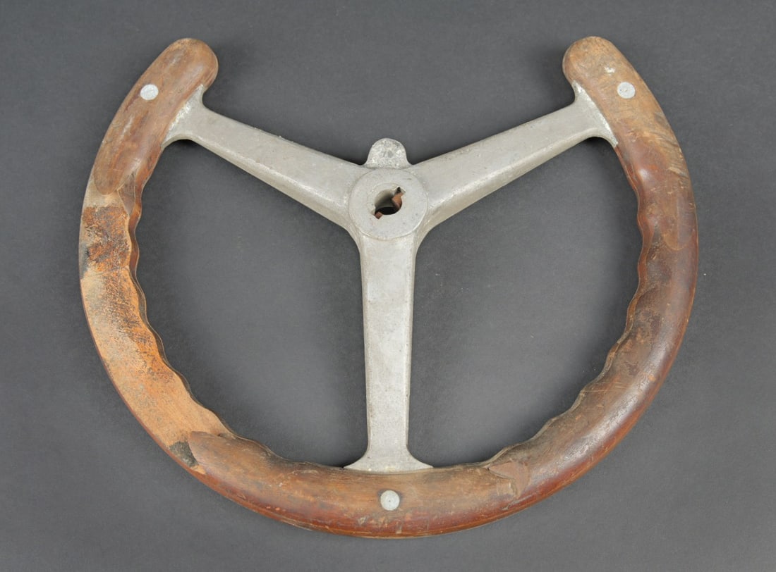 Volant d avion. Aircraft control wheel.: Volant d avion. Probablement pour un DC 3 ou peut etre un Fokkers. Armature en aluminium. Les mains se posent sur une partie en bois ronde. Le cercle est incomplet. Nombreuses fissures visibles. Marqu