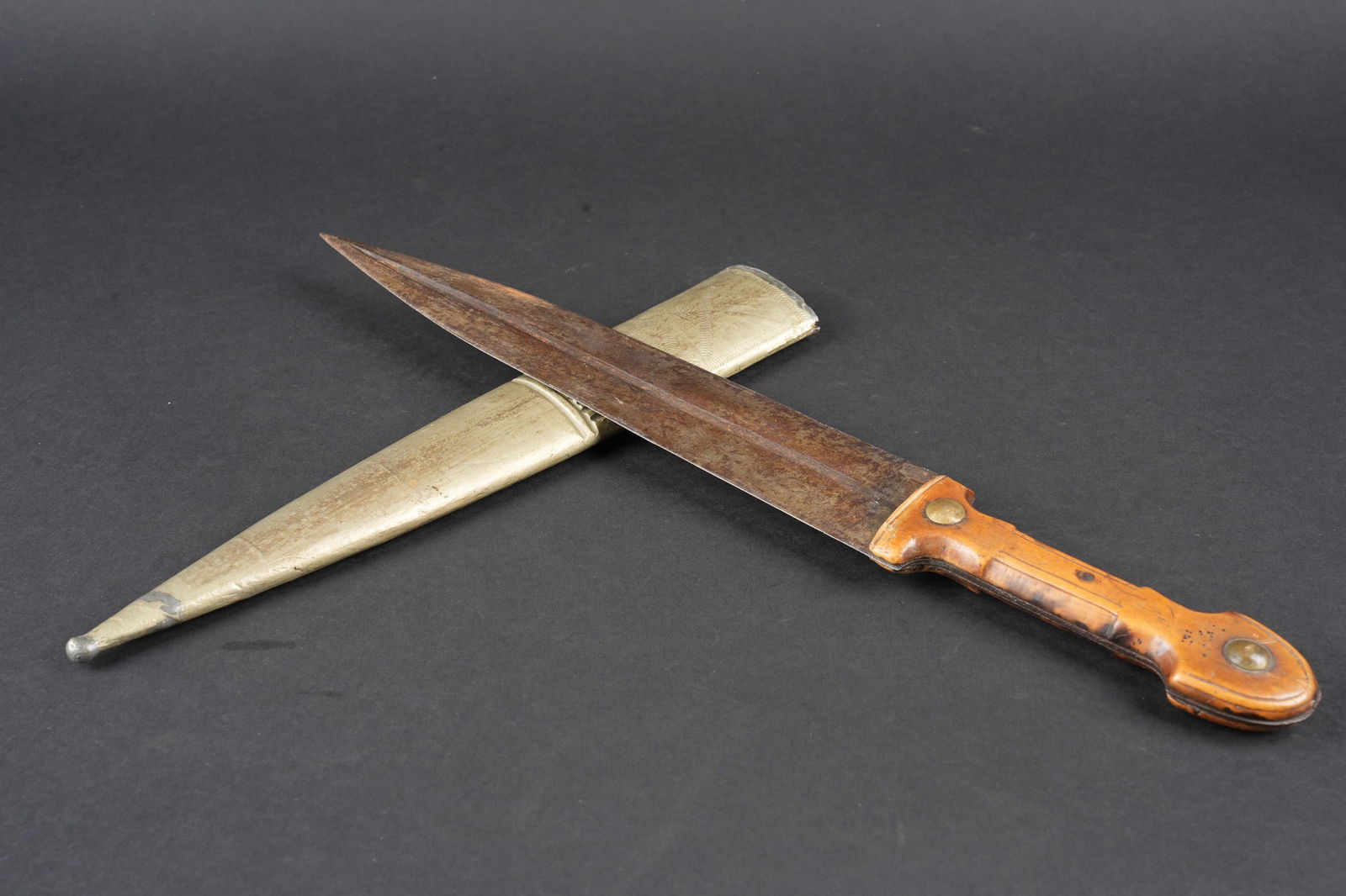 Poignard Kindjal. Kindjal dagger: Poignard Kindjal. Lame en acier a double tranchant, une gorge centrale. Decor central legerement visible, manche compose de deux plaquettes cintrees en bois. Fourreau en bois recouvert de metal fin, p
