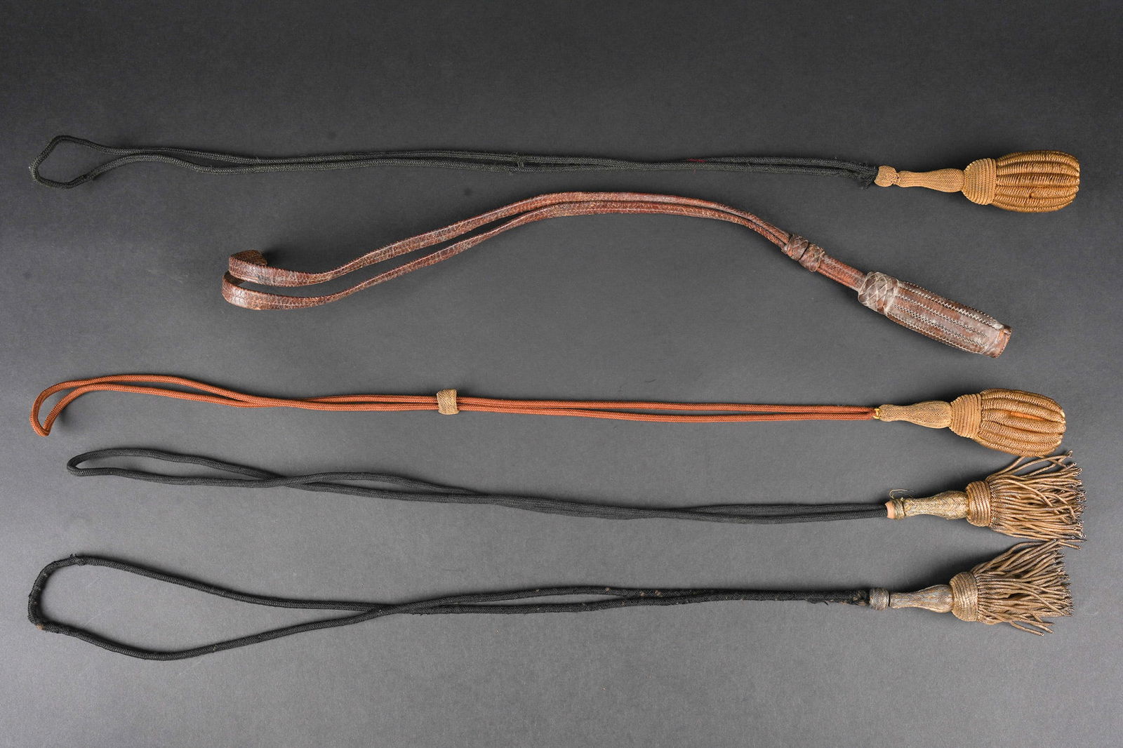 Ensemble de dragonnes. Set of sword knots.: Ensemble de dragonnes. Comprenant cinq dragonnes dont une de sabre 1882 en cuir fauve, deux dragonnes de sabre d officier pour petite tenue, deux dragonnes de sabre d officier IIIeme republique avec c