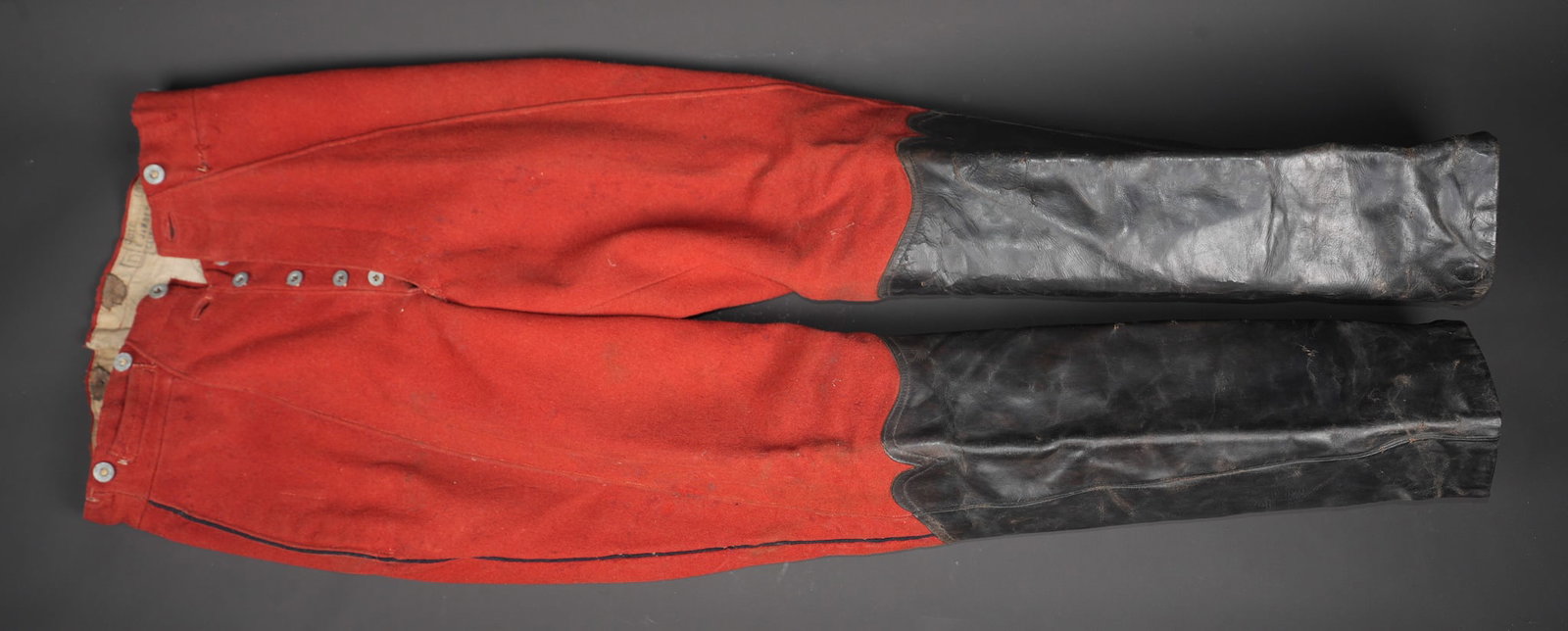 Pantalon a basane de cavalerie. Cavalry breeches with leather reinforcements.: Pantalon a basane de cavalerie. Pantalon en fort drap garance, passepoil bleu ciel, renforce de drap garance au fessier et a l entrecuisse. L effet se termine pas des basanes en cuir en fausse bottes