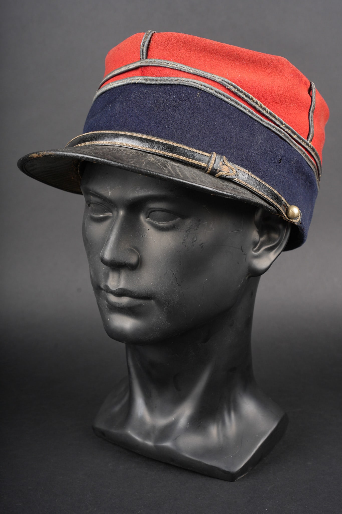 Kepi de lieutenant du Train. Train lieutenant’s kepi.: Kepi de lieutenant du train. Confectionne en drap garance, bandeau en drap bleu fonce, grades de lieutenants cousus d origine. Fausse jugulaire en cuir laque, borde d un en cannetille et retenue par d