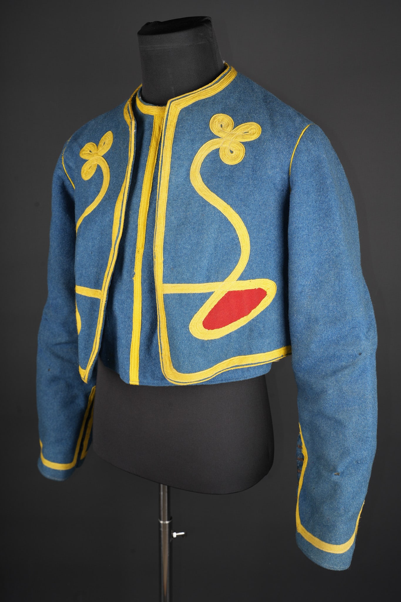 Veste bolero et gilet tirailleur. Tirailleur bolero jacket and waistcoat.: Veste bolero et gilet tirailleur. Veste bolero en tissu bleu ciel et tombeaux garance, garnitures et tresses d ornement jonquille, les manches se resserrent a l aide de six crochets dont un accidente.