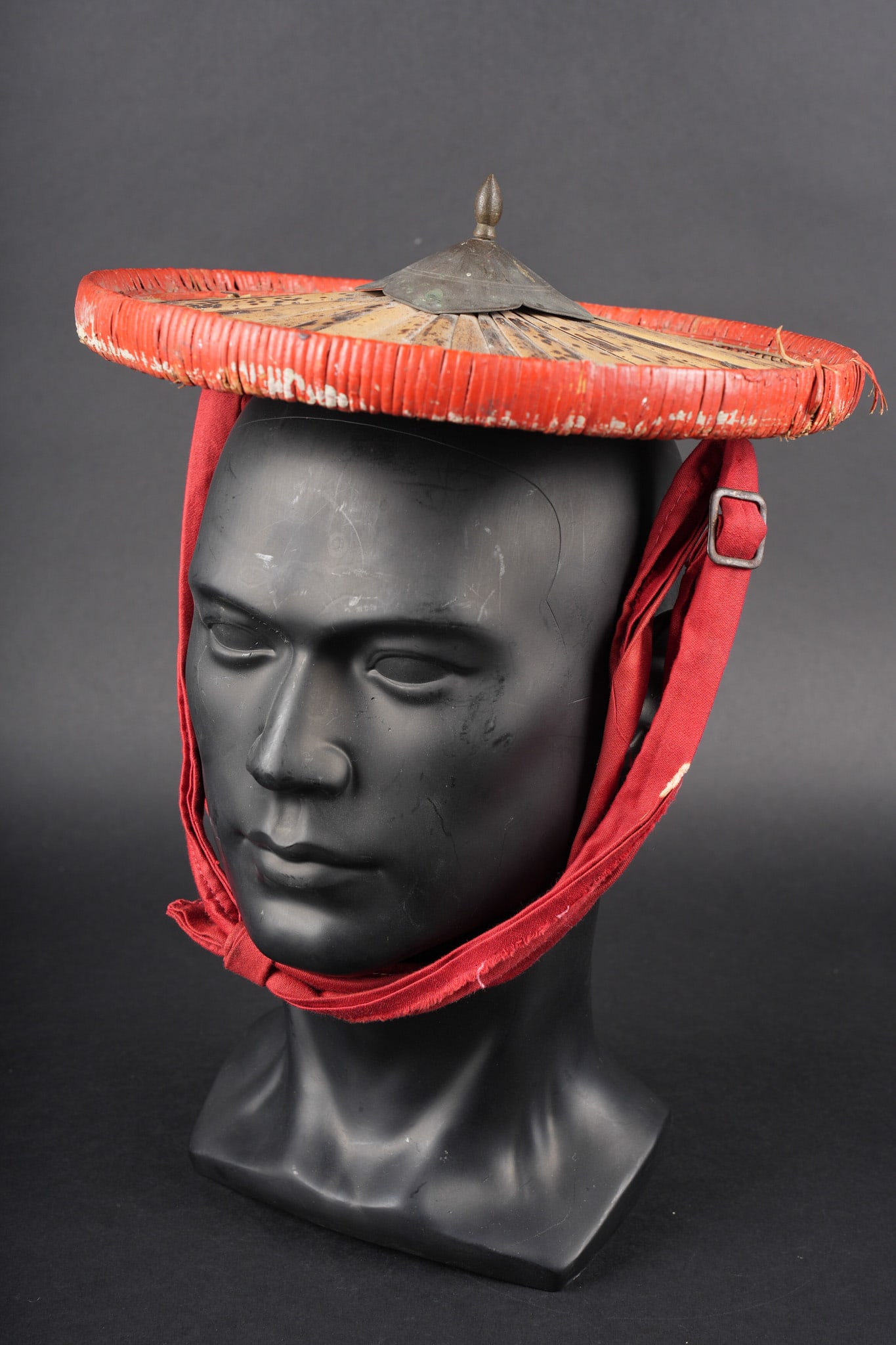 Salako tirailleur Annamite. Tirailleur salacco Salamite type.: Salako tirailleur Annamite. Salako de forme ronde en lamelles de bambous et paille de riz. Large bordure teintee en rouge, pointe en laiton retenue par une goupille. Jugulaire en coton garance reglabl