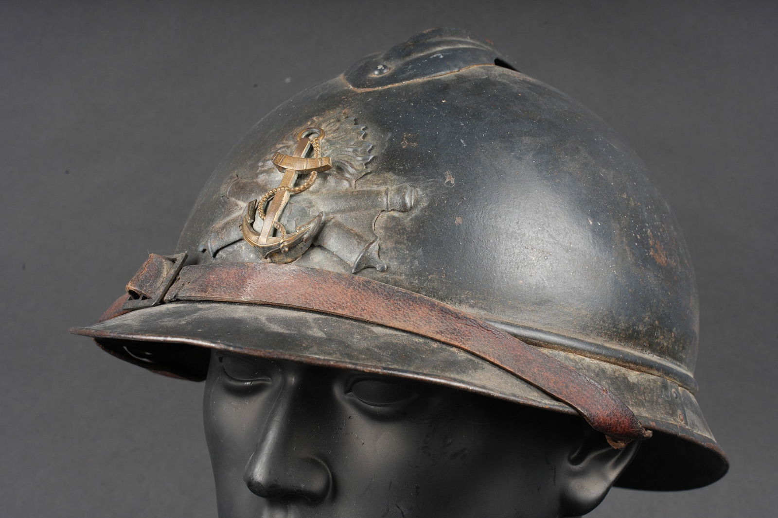 Casque Adrian 1915 artillerie coloniale. Adrian helmet Model 1915, Colonial Artillery.: Casque Adrian 1915 artillerie coloniale. Casque modele 1915 en peinture bleu horizon recouverte d une seconde couche plus foncee. Attribut de l artillerie modele 1915 sur lequel a ete replacee une