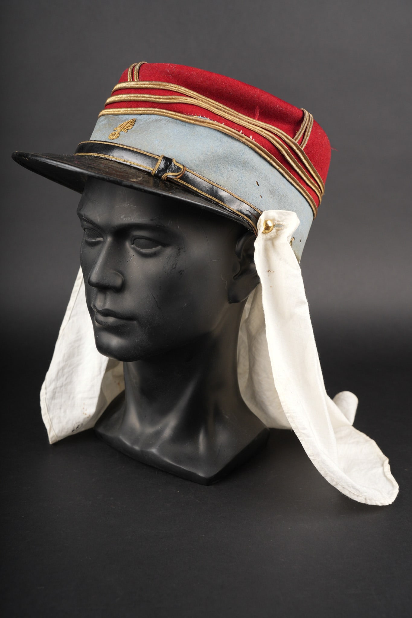 Kepi d un capitaine des tirailleurs. Tirailleur captain’s kepi.: Kepi d un capitaine des tirailleurs. Kepi de capitaine tirailleurs et troupes indigenes rattache a un etat major, confectionne en drap garance, bandeau bleu clair. Grenade frontale brodee cannetille,