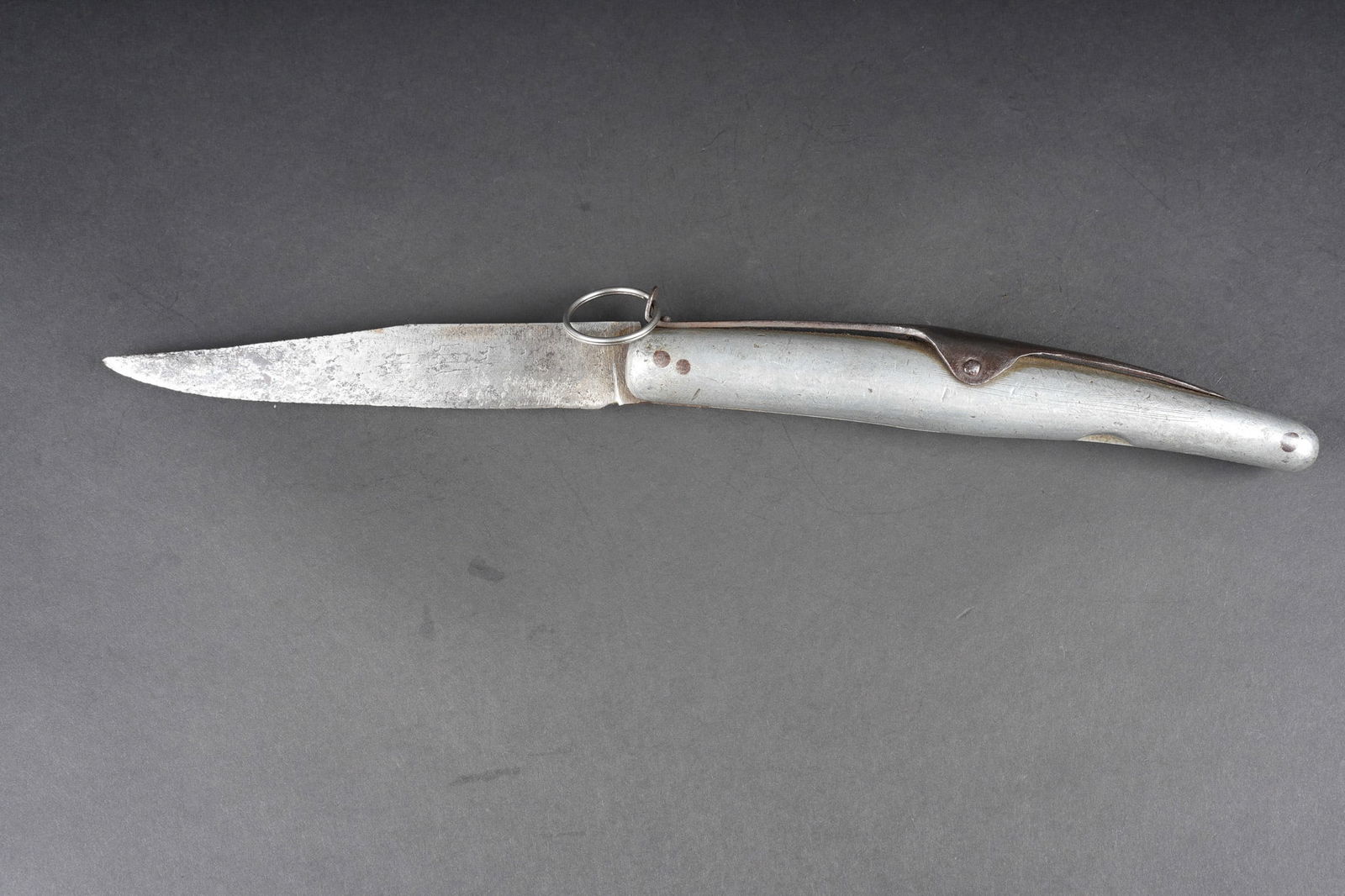 Couteau a cran d arret en aluminium. Aluminium folding knife: Couteau a cran d arret en aluminium. Manche entierement en aluminium, pas de marquage fabricant sur la lame fortement affutee. Cran d arret fonctionnel, anneau posterieur. Longueur totale 37cm.