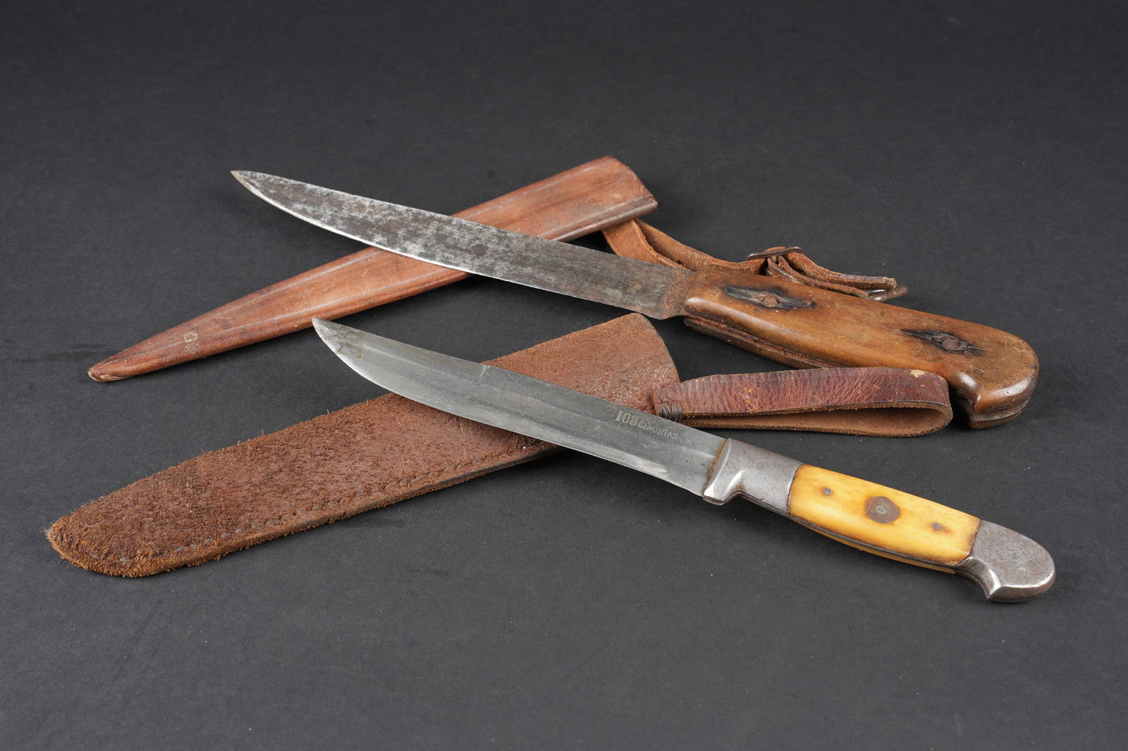 Couteaux type boucher. Butcher-type knives: Couteaux type boucher. Comprenant un couteau avec un manche en bois portant la mention 14, 15, 16, 17, lame fortement affutee. Fourreau artisanale en cuir brun avec un passant a anneau. Un couteau