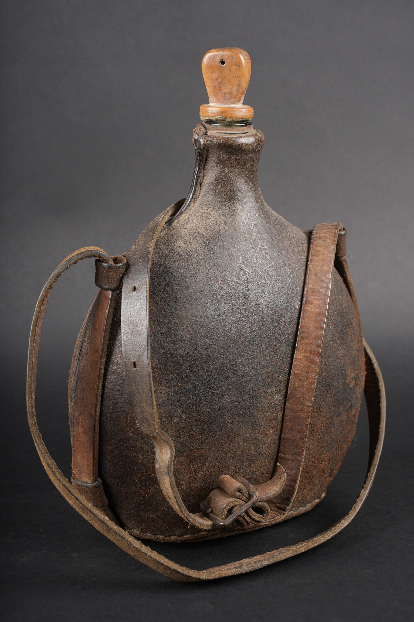 Gourde en verre. Glass water bottle: Gourde en verre. Belle gourde en verre reprenant la forme du bidon 1877, recouverte d une housse en cuir. Brelage en cuir d origine, bouchon en bois. Effet typique des achats personnel pour officier.