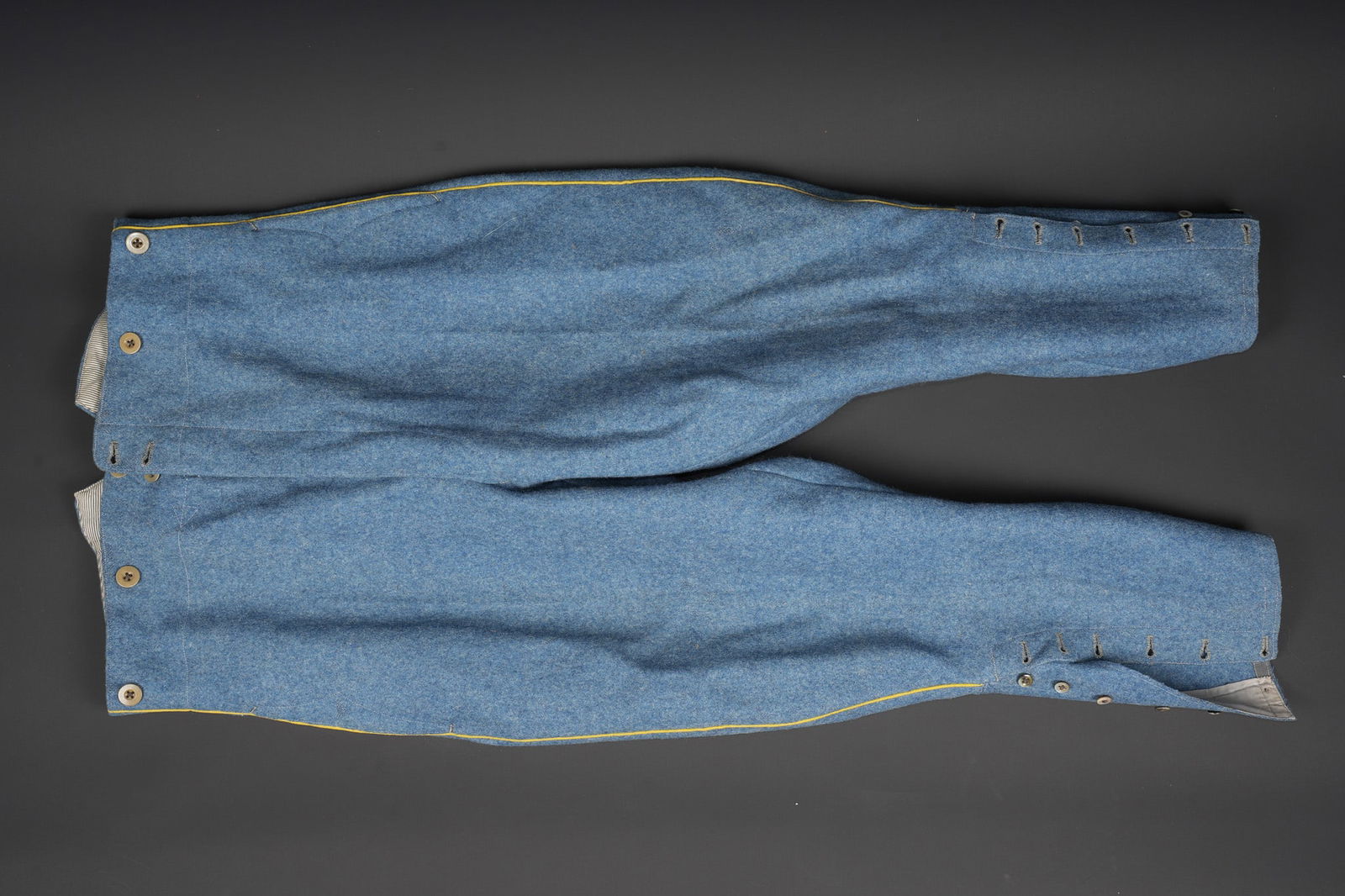 Culotte infanterie bleu horizon. Horizon-blue infantry breeches: Culotte infanterie bleu horizon. Culotte de sous officier confectionnee en drap bleu horizon, passepoil jonquille pour l infanterie, manchettes se fermant par six boutons. Doublure en coton raye,